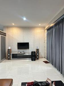 a living room with a flat screen tv on a wall at Villa Mahlin 3 kamar in Tutugan +9 photos