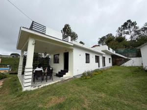 a white house with a table in a yard at The White Haven Kotagiri in Kotagiri