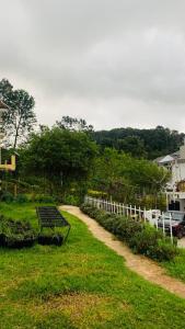 a bench sitting in the grass next to a white fence at The White Haven Kotagiri in Kotagiri