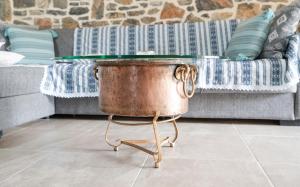 a copper pot on a stand in front of a couch at Πέτρινο Αλώνι in Panayía