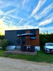 a house with a table and an umbrella and a car at Tinyhaus Altmühlauszeit in Beilngries