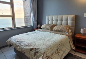 a bedroom with a bed with a view of the ocean at Scottburgh Views 707 Seafront Apartment in Scottburgh +43 photos