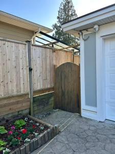 a backyard with a fence and a garden with flowers at Spacious 2 Bedroom Suite in Burnaby Free Parking, Full Kitchen, Near Transit in Burnaby