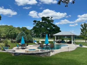 a pool with chairs and umbrellas and a gazebo at Cozy Luxury Cottage in Alachua