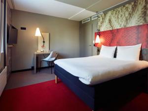 a hotel room with a large bed and a desk at ibis Zürich Messe Airport in Zurich +100 photos