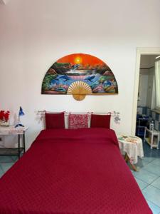 a bedroom with a red bed with a painting on the wall at Ponzamania Casa dei fiori in Ponza