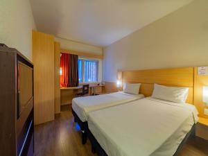 a hotel room with two beds and a television at ibis Manaus Distrito Industrial in Manaus