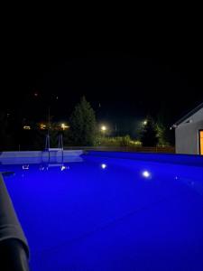a large blue swimming pool at night at Boiko house - котеджі з чаном-джакузі та басейном in Slavske +14 photos