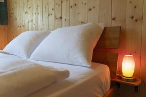 a bed with white pillows and a lamp on a table at Bergpanorama in Wildhaus