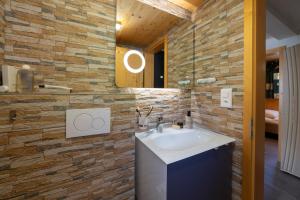 a bathroom with a sink and a stone wall at Bergpanorama in Wildhaus +11 photos