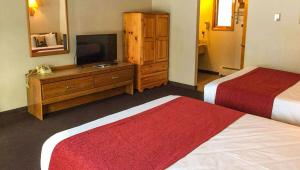 a hotel room with two beds and a flat screen tv at Adirondack Lodge Old Forge in Old Forge