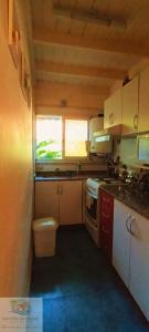 a small kitchen with white cabinets and a window at Duplex in Pinamar