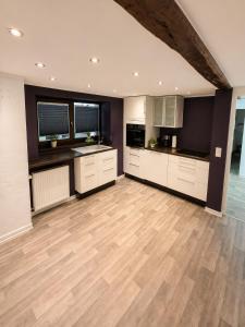 a large kitchen with white cabinets and a wooden floor at Gemütliche Ferienwohnung in Hackenheim