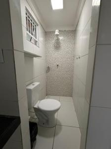 a white bathroom with a toilet and a shower at Pousada Sol Brasil in Fortaleza