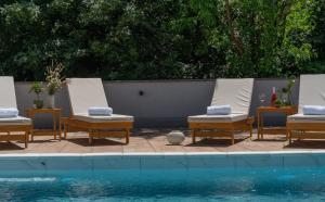 a group of lounge chairs next to a swimming pool at MB Villas in Vrnjačka Banja