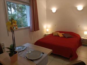 a bedroom with a red bed and a table and a window at Résidence de la Source by Euclenima in Salies-de-Béarn +52 photos