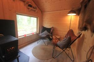 a room with chairs and a stove in a cabin at Forest Shed in Åsele