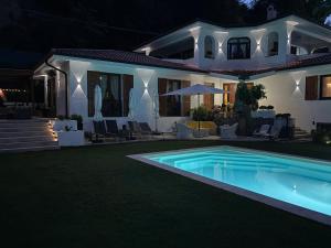 a house with a swimming pool at night at VILLA ROMA Resort in Vallecrosia