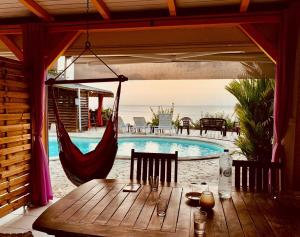 a table with a hammock on a patio with a pool at kazAnne in Pointe-Noire