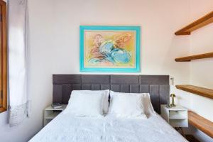 a bedroom with a bed and a painting on the wall at Piscina com ofurô/Churrasqueira/Sinuca e Ping Pong in Caraguatatuba