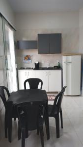 a kitchen with a black table and chairs in a room at Casinha Larithur in Beberibe