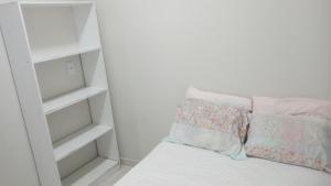 a white room with a bed with pillows on it at Casinha Larithur in Beberibe