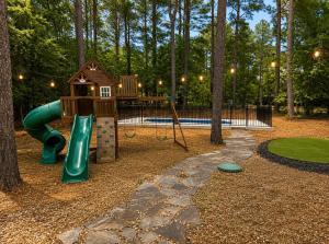 a park with a playground with a slide and a house at Big Pine Gathering - Heated Pool - Pickleball - Sleeps 16 in Broken Bow