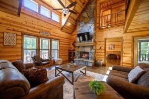a living room with couches and a fireplace in a log cabin at Big Pine Gathering - Heated Pool - Pickleball - Sleeps 16 in Broken Bow