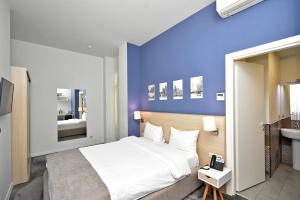 a bedroom with a white bed and a blue wall at In City Hotel in Yerevan