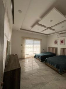 a bedroom with two beds and a table and a window at Al Salty in Tall ar Rāmah +18 photos
