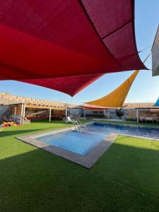 a building with a swimming pool and a red umbrella at Al Salty in Tall ar Rāmah