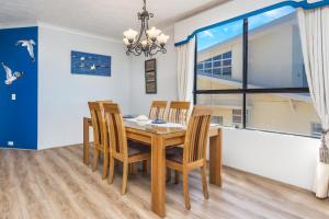 una sala da pranzo con tavolo, sedie e una finestra di Sunset Sails Penthouse Redcliffe a Redcliffe