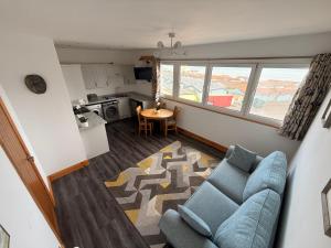 a living room with a blue couch and a kitchen at Flat White in Westward Ho