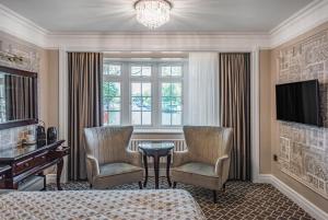a bedroom with two chairs and a table and a television at Riverside Inn in Ely