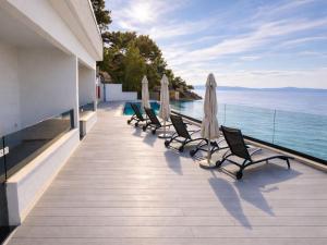 a row of chairs and umbrellas on a balcony with the ocean at ADRIA MIRIS apartments in Drasnice