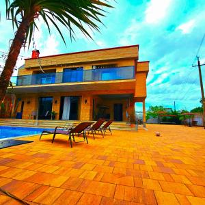 a house with chairs and a pool in front of it at Villa "Rezi-dencia" in Batumi