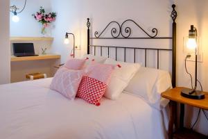 a bedroom with a white bed with red and white pillows at El Fresquedal in Alozaina +87 photos