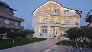 a large white building with chairs in front of it at Vila Astrit in Fier