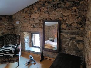 a bedroom with a stone wall with a mirror at Casa do Baloiço em Porto de Vacas Aldeias de Xisto in Janeiro de Baixo