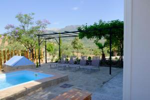 a patio with a swimming pool and chairs and aented at El Fresquedal in Alozaina