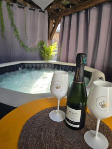a bottle of wine and two glasses on a table next to a tub at Sarments et Bulles in Ambonnay