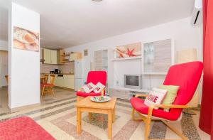 a living room with two red chairs and a table at Apartment Seaside Peace in Vela Luka