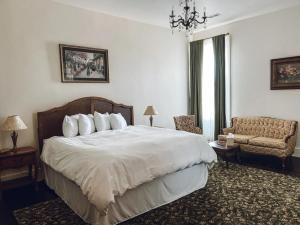 a bedroom with a bed and a chair and a chandelier at Historic Knox Hotel in Princeton
