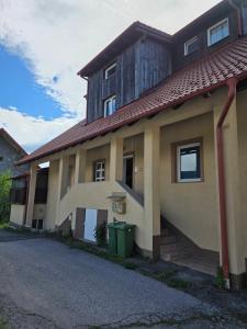 a house with a building with a green trash can at Apartman Gorski raj in Fužine