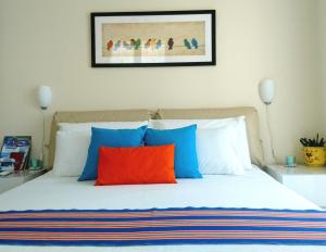 a bedroom with a bed with blue and orange pillows at Nerissa Holiday Apartment Milazzo in Milazzo