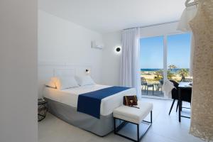 a bedroom with a bed and a desk and a balcony at Sea View Hotel Fronte Mare in San Vito lo Capo
