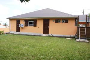 una casa con un césped verde delante de ella en villa sofaia Guadeloupe, en Sainte-Rose