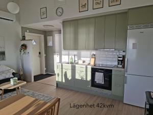 a kitchen with green cabinets and a white refrigerator at Ellas Brygga in Karlskrona