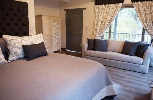 ein Schlafzimmer mit einem Bett, zwei Sofas und einem Fenster in der Unterkunft Hotel MasClara in Villa de Leyva