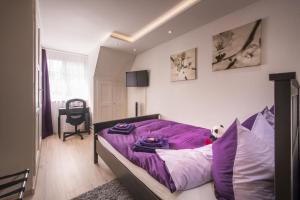 a bedroom with a purple comforter on a bed at Max Aviation Villa & Apartments in Bern